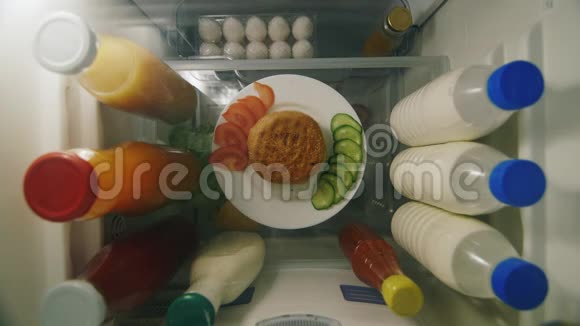 一个男人手拿着一个汉堡和一个酱汁从冰箱过夜零食和不健康的非正式膳食顶部视图视频的预览图