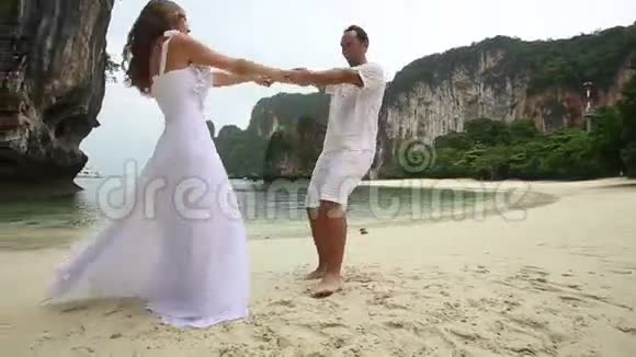 在沙滩上新娘和新郎携手共进视频的预览图