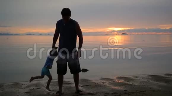 日落时分抱着孩子在沙滩上兜圈子的人视频的预览图