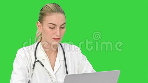 严肃的女医生在绿色屏幕上的笔记本电脑上工作Chroma键视频的预览图