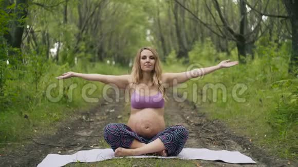 美丽的孕妇在户外做产前瑜伽怀孕期间的运动健身健康生活方式视频的预览图