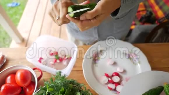 年轻女子在木桌上切黄瓜做沙拉高清慢镜头视频的预览图