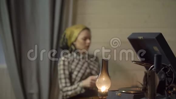 裁缝女孩休息喝茶用煤油灯放松在乙烯基板上听音乐留声机或留声机视频的预览图