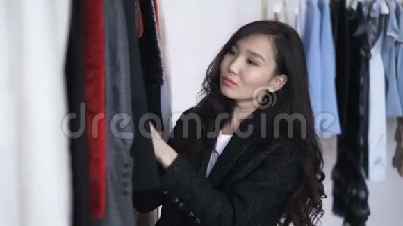 有魅力的亚洲年轻女子在商店里挑选冬季服装视频的预览图