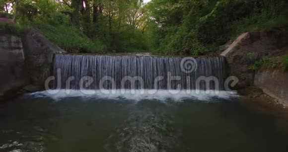 森林边缘一条小河上瀑布的鸟瞰图视频的预览图