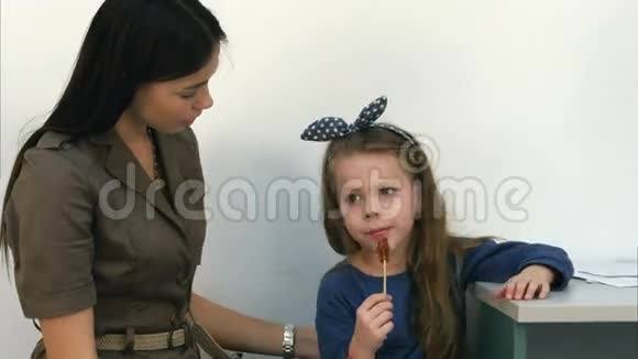 微笑的母亲和她的小女孩在医生办公室吃棒棒糖聊天视频的预览图