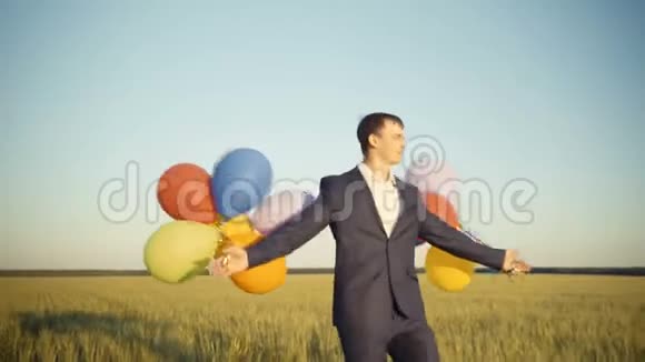 创意商人手持五颜六色的气球在一个田野散步视频的预览图