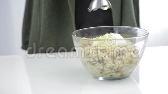 女人把坚果和干果混合在玻璃碗里烹饪健康食品视频的预览图