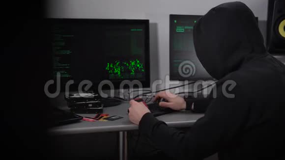 一个蒙面黑客对银行网络进行网络攻击的背面视图穿黑衣服的人在键盘上打字很快视频的预览图