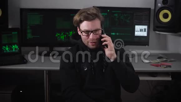 机房里的那个人戴眼镜的年轻人坐在椅子上用他专注的智能手机说话关于视频的预览图