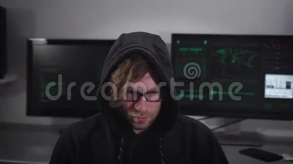 关闭一个间谍与智能手表坐和使用笔记本电脑与电脑显示器在他后面戴眼镜的罪犯视频的预览图