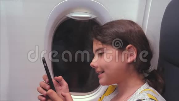 航空飞机概念小女孩正坐飞机在窗户旁边聊天看着里面视频的预览图