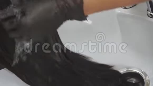 美发师手上的特写师父在一家黑色的美容院洗头发视频的预览图