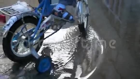 一个孩子骑着孩子自行车穿过水坑视频的预览图
