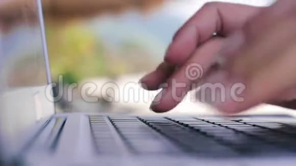 从宏观上看女人的手在户外的笔记本电脑上打字视频的预览图