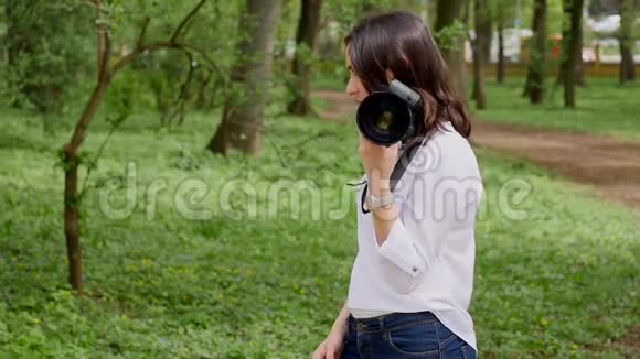 年轻女性摄影师在公园大自然户外拍摄视频的预览图