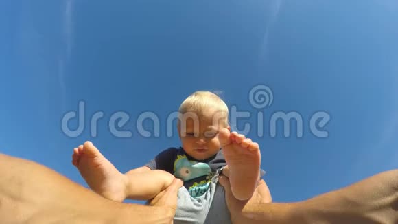 在一个阳光明媚的日子里父亲举起了他的小儿子爸爸在大自然里和可爱的宝宝玩背景蓝天视频的预览图