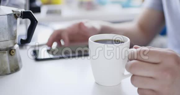 男人坐在桌子上拿着智能手机喝着新鲜的热饮视频的预览图