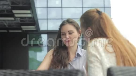 两个年轻女人在户外咖啡馆里讨论文件问题视频的预览图