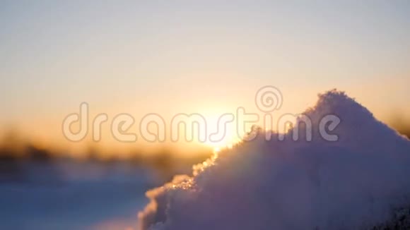 女孩在日落的背景下用手吹雪冬霜日视频的预览图