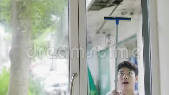 男孩用玻璃布擦房子微笑的脸年轻的亚洲男孩清洁镜子在家里视频的预览图