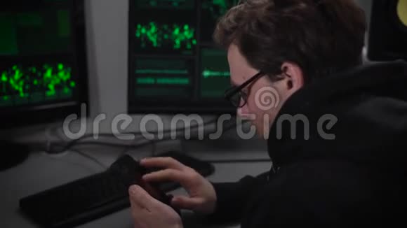 地下组织桌上有两台电脑和一台笔记本电脑一个穿着深色夹克戴着眼镜的男人看着视频的预览图