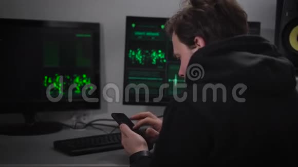 成年男性黑客脸上有胡茬穿着黑色运动夹克坐在秘密掩体里制造网络视频的预览图