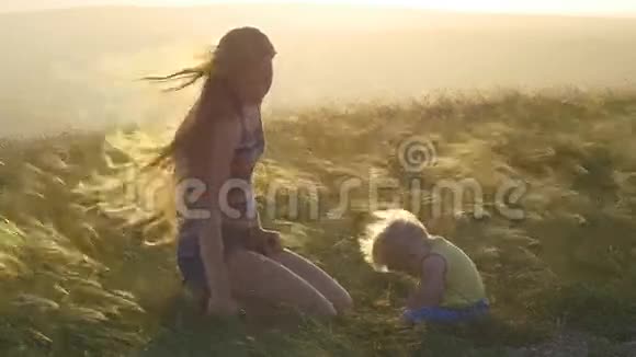 日落时分母亲和孩子在草地上视频的预览图