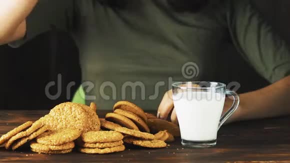 用手慢慢地把一块饼干放进一杯牛奶里食物电影场景视频的预览图