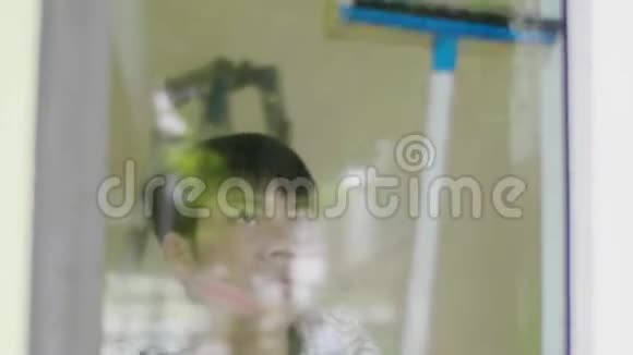 男孩用玻璃布擦房子微笑的脸年轻的亚洲男孩清洁镜子在家里视频的预览图