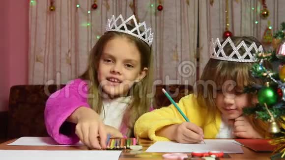 两个女孩在桌旁画画有趣的一个选择想要的彩色铅笔视频的预览图