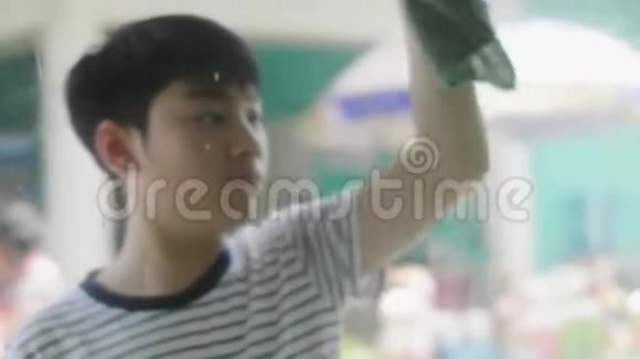 年轻的亚洲男孩在家清洁镜子视频的预览图