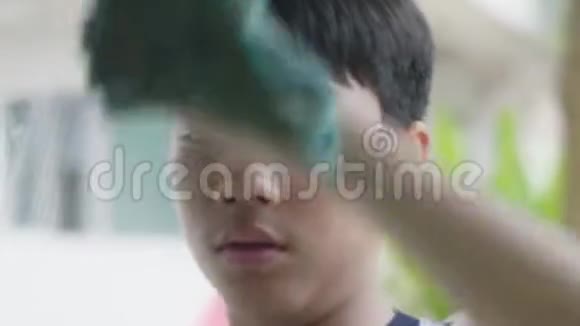 年轻的亚洲男孩在家清洁镜子视频的预览图
