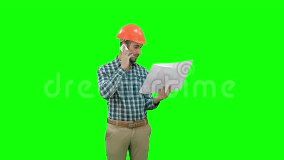 现场经理在电话里讲话手里拿着绿色屏幕上的蓝图Chroma键视频的预览图