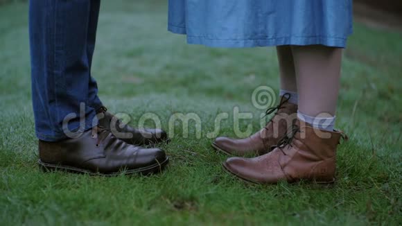 穿着牛仔裤和靴子在草地上行走的女性和男性的腿紧贴着视频的预览图