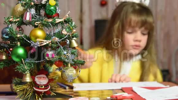 女孩在桌边画圣诞图案专注于她面前的皮草树视频的预览图