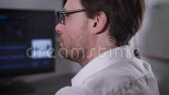 那个戴着眼镜和白衬衫的人很快就在电脑键盘上打字盯着显示器看视频的预览图