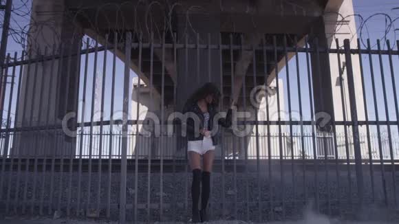 美丽的女孩呆在桥下的栅栏附近工业区时尚视频视频的预览图