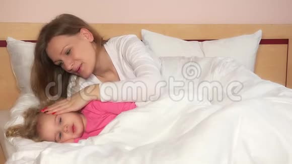 母亲抚摸她躺在床上的女孩子使她入睡视频的预览图