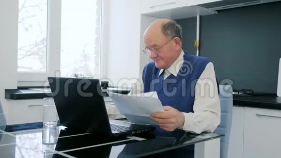 退休老人在电脑上工作厨房里有文件视频的预览图
