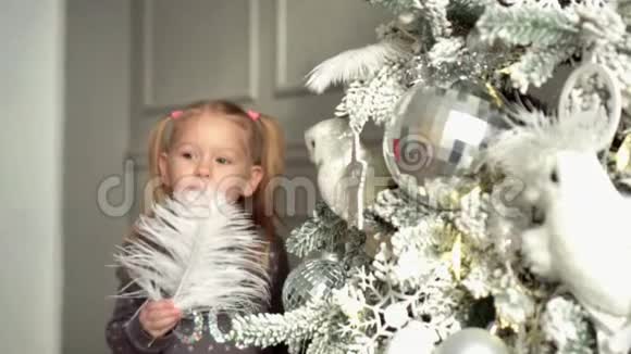 这个女孩在一棵新年树旁边玩树上有一根白色的羽毛视频的预览图