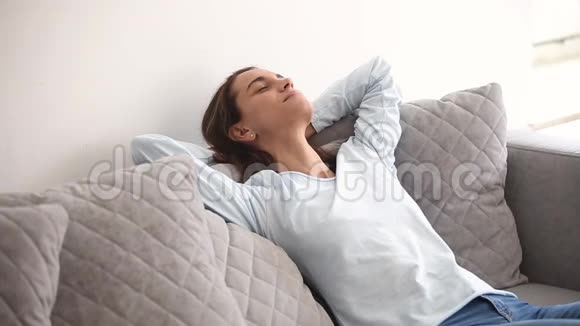 千禧一代的女人闭上眼睛躺在舒适的沙发上视频的预览图