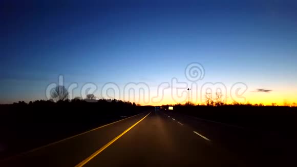 日出时驾驶农村公路司机的观点POV而太阳升起在地平线上的清晨视频的预览图