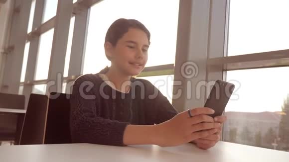 十几岁的女孩正在聊天在生活方式中的智能手机里在一张桌子上的咖啡馆里交流视频的预览图
