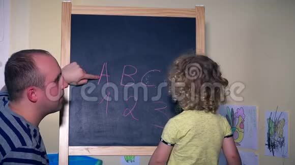 男子和小女孩在粉笔黑板上学习数字和字母视频的预览图