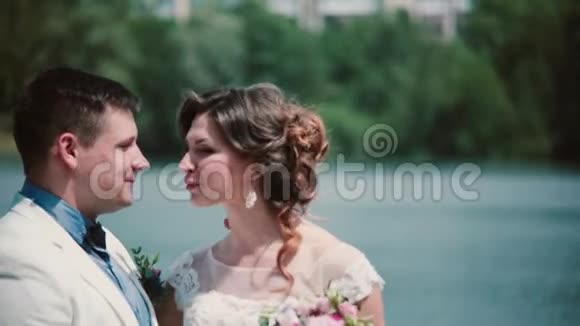 结婚纪念日美丽的夫妇在码头上接吻享受他们的幸福结婚礼服花束视频的预览图