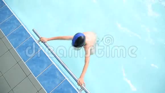 小男孩在游泳池里的水里游泳视频的预览图