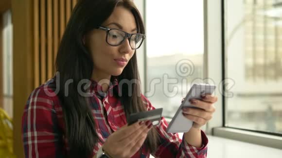 年轻的混血时髦女人拿着信用卡用手提电脑视频的预览图