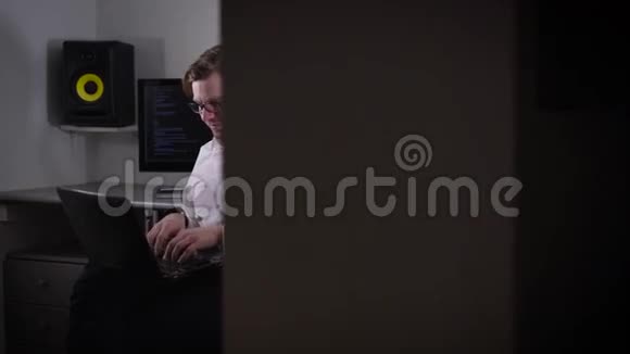 一个年轻人在笔记本电脑上工作手上拿着智能手表设置他的小工具的肖像当代发展者视频的预览图