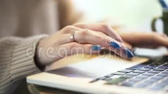 女人用蓝色指甲油在笔记本电脑上打字平底锅射击视频的预览图
